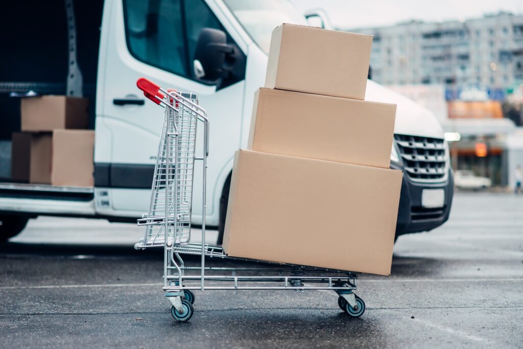 Trolley with boxes against truck, male logistic
